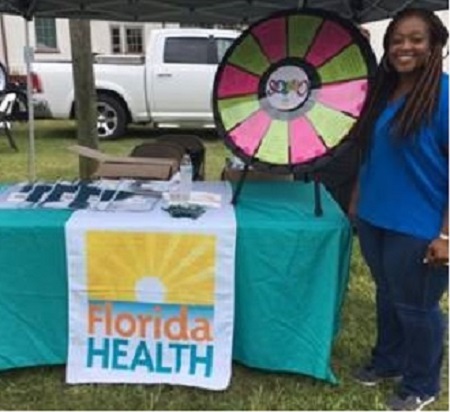 DOH-Franklin/Gulf Health Educator Talitha Robinson posing with the health wheel at the Back-to-School Bash.